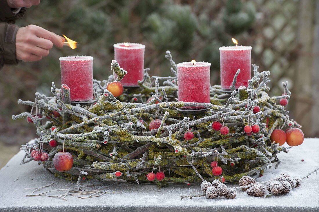 Adventskranz aus bemoosten Zweigen auf Metallgestell mit Kerzenhaltern