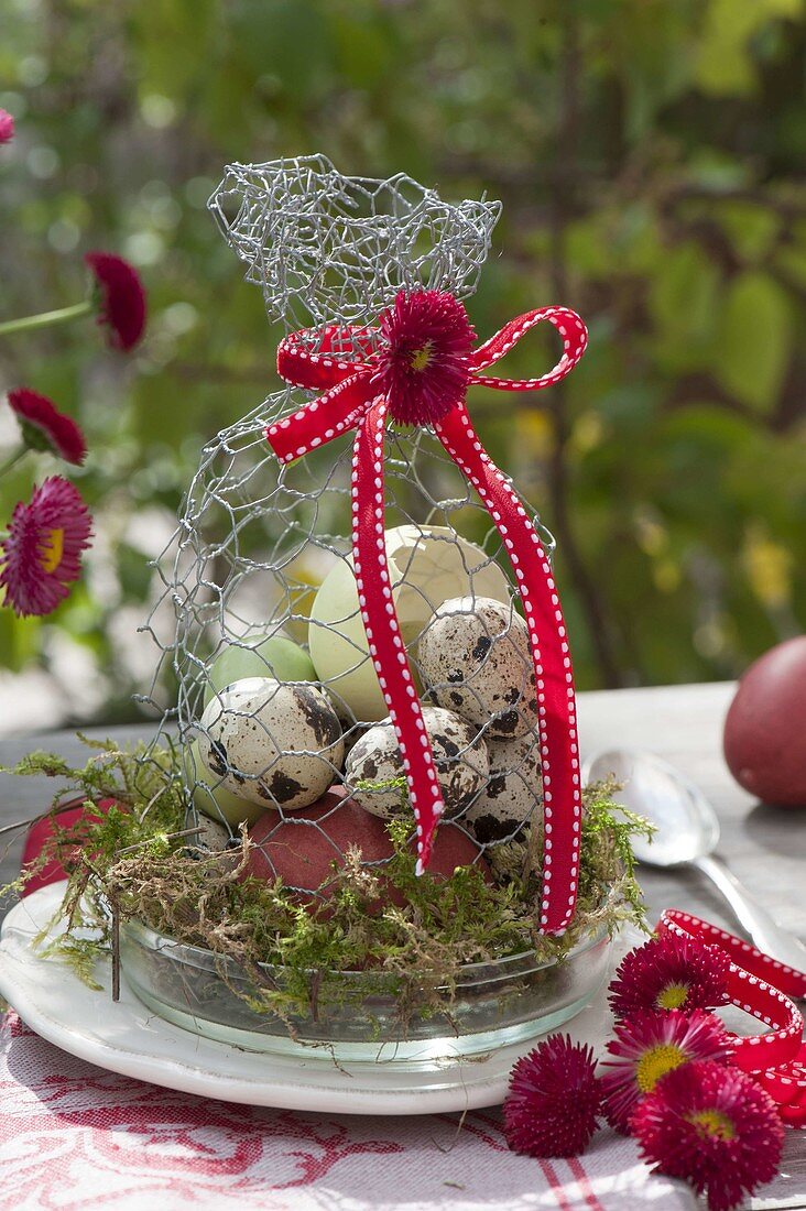 Easter eggs under hood made of chicken wire on cup with moss