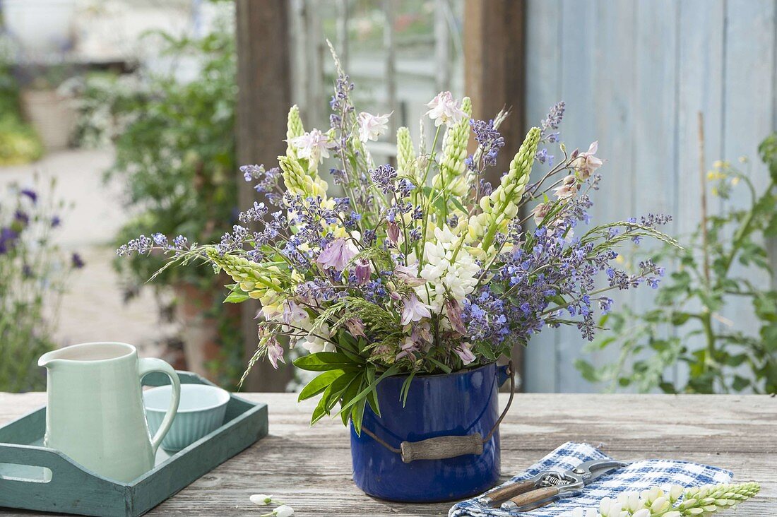 Bouquet made of early summer perennials in blue enamel bucket