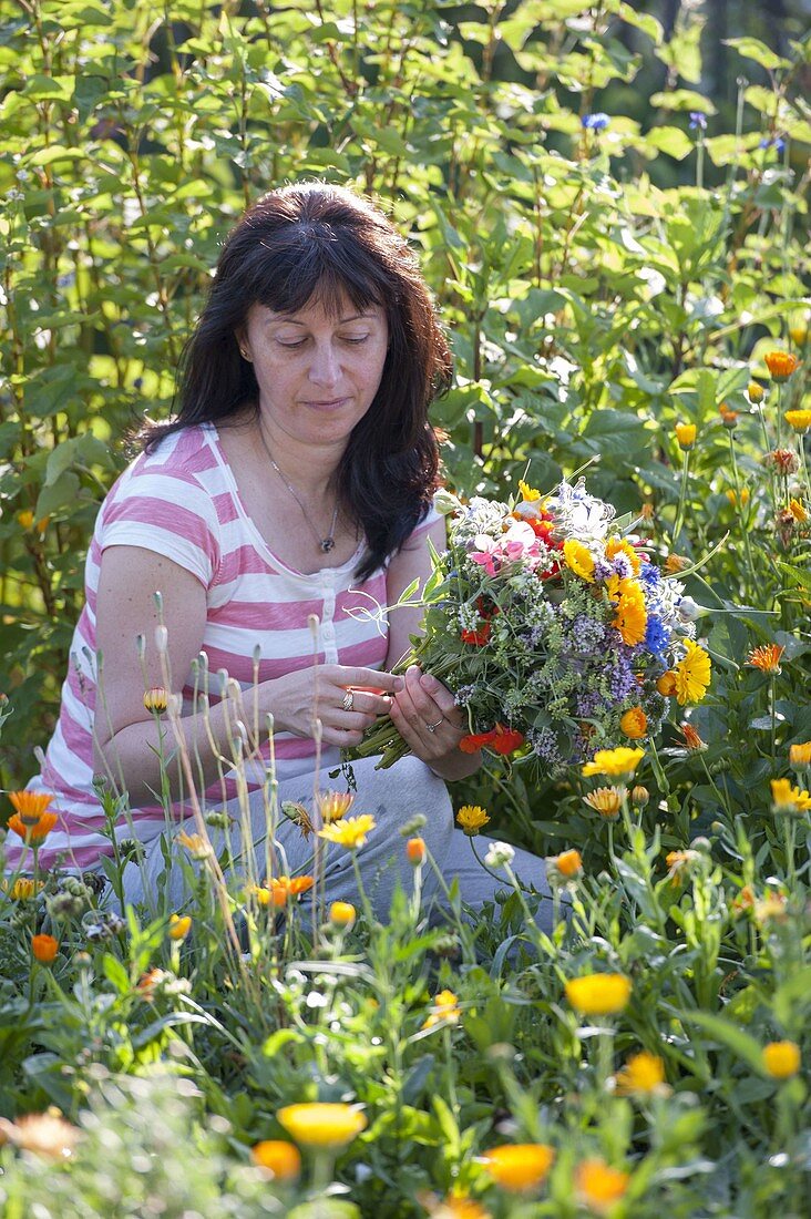 Woman picking bouquet from everything that blooms in the cottage garden