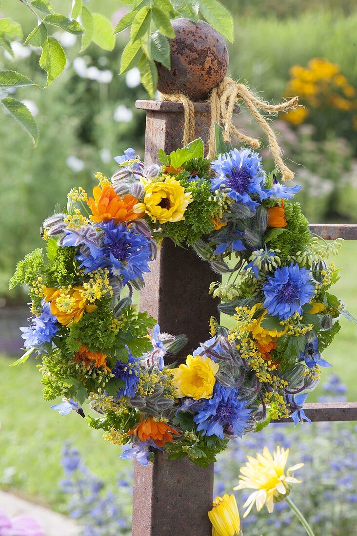 Blau-gelb-oranger Kranz aus essbaren Blüten und Kräutern