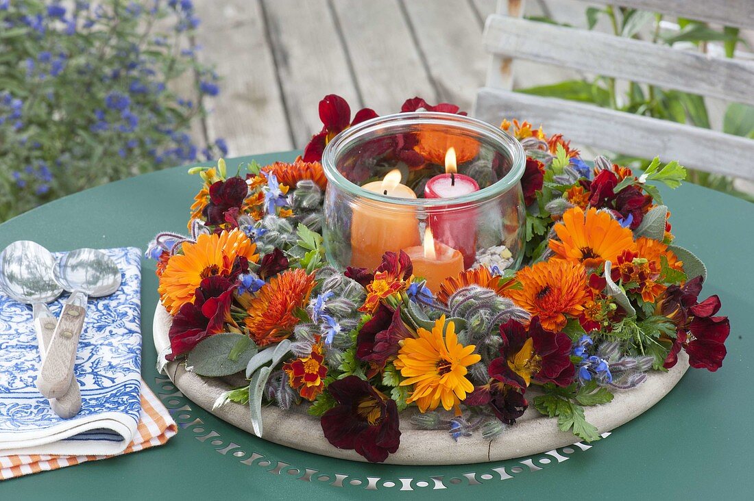 Wreath made of edible flowers and herbs with preserving jar as a lantern