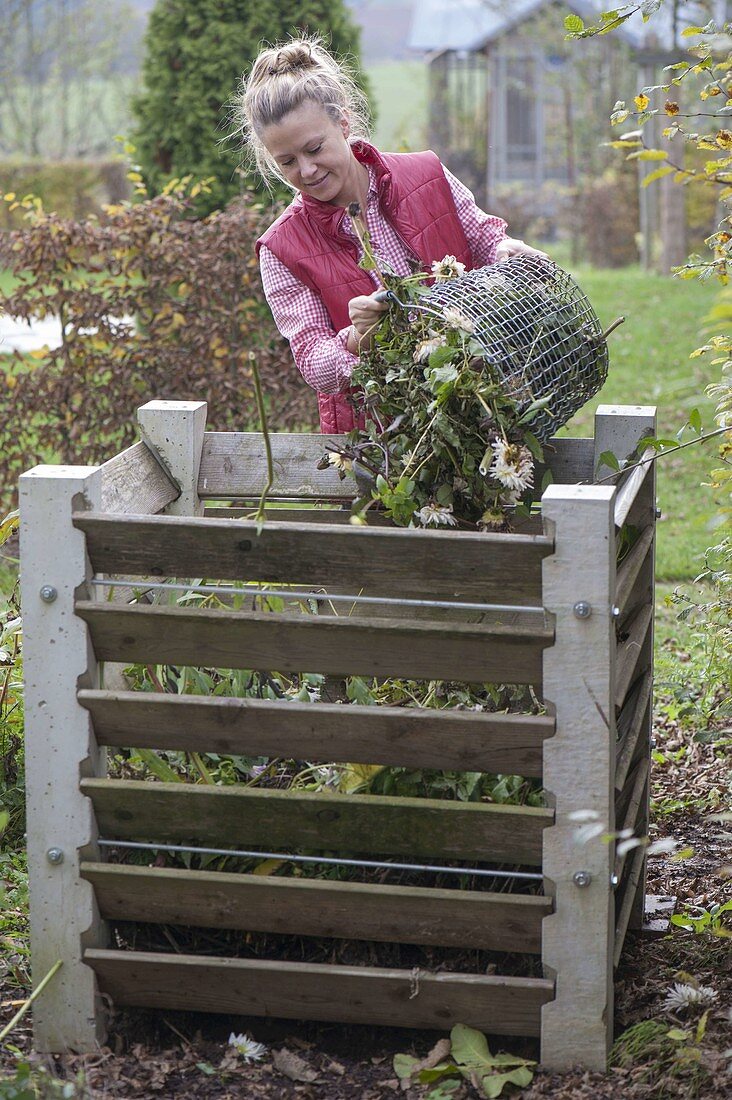 Frau schüttet Gartenabfälle in den Kompost-Behälter