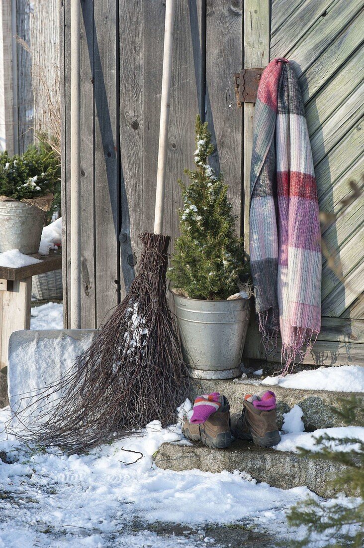 Stillleben am Geräteschuppen mit Schneeschaufel, Reisigbesen, Picea