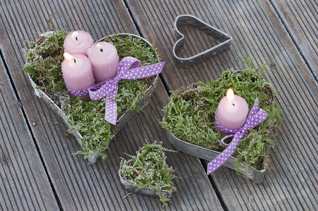 Candles in moss-filled heart shapes and purple ribbon