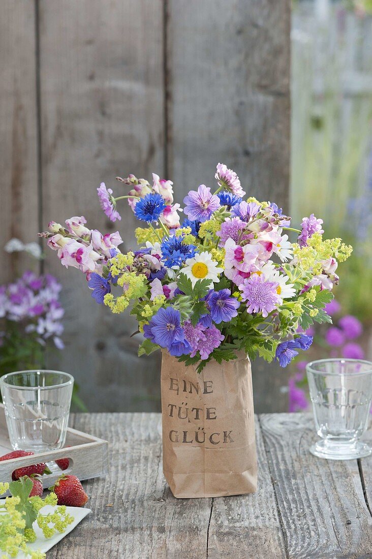 Small bouquet of perennials and summer flowers in a printed paper bag