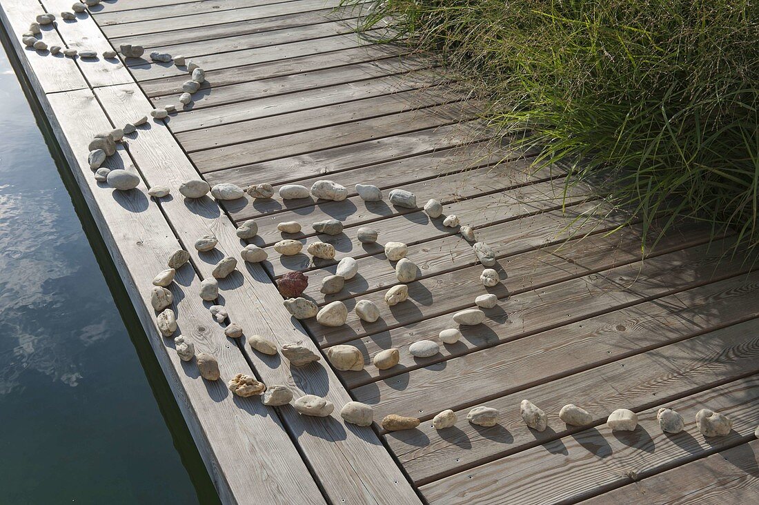 Spiral of pebbles laid on boardwalk at the swimming pond