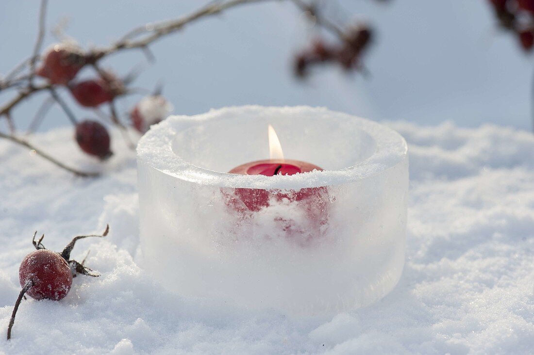 Rote Kerze in Windlicht aus Eis