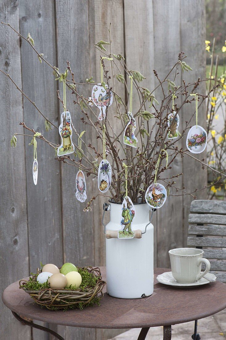 Osterstrauss aus Zweigen in alter Milchkanne, geschmückt mit Oster-Oblaten