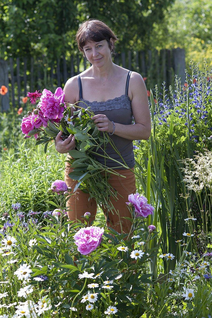 Woman is cutting flowers for bouquet