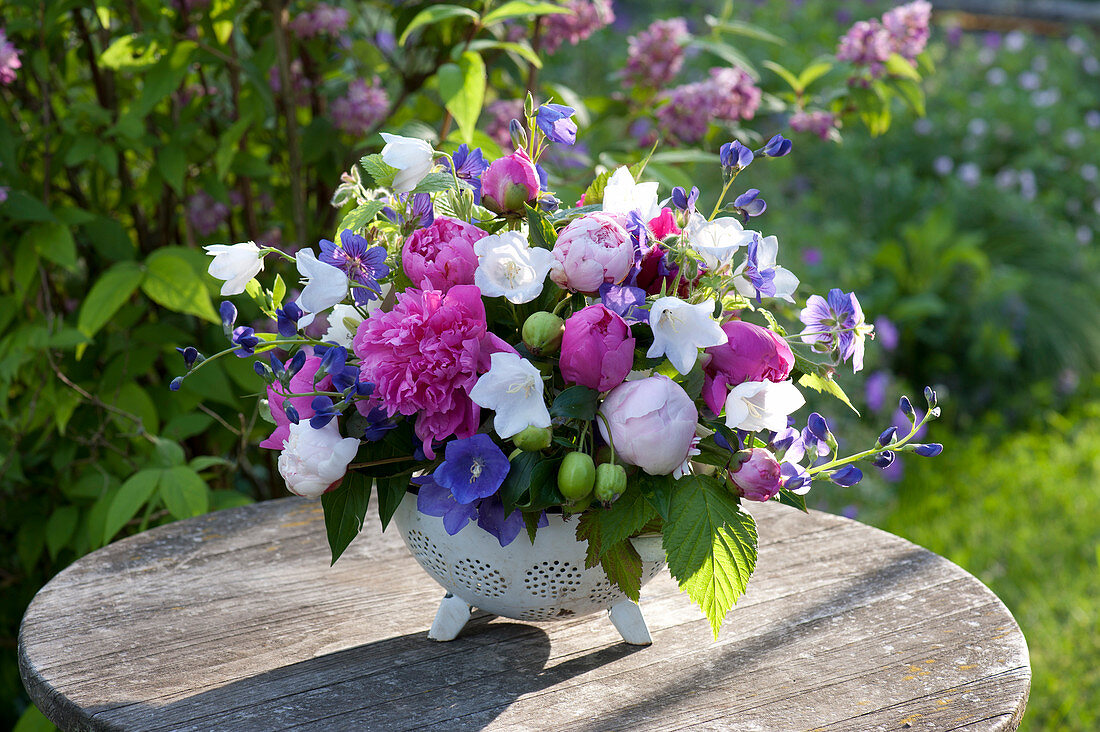 Arrangement made of Paeonia (Peony), Campanula in the enameled sieve