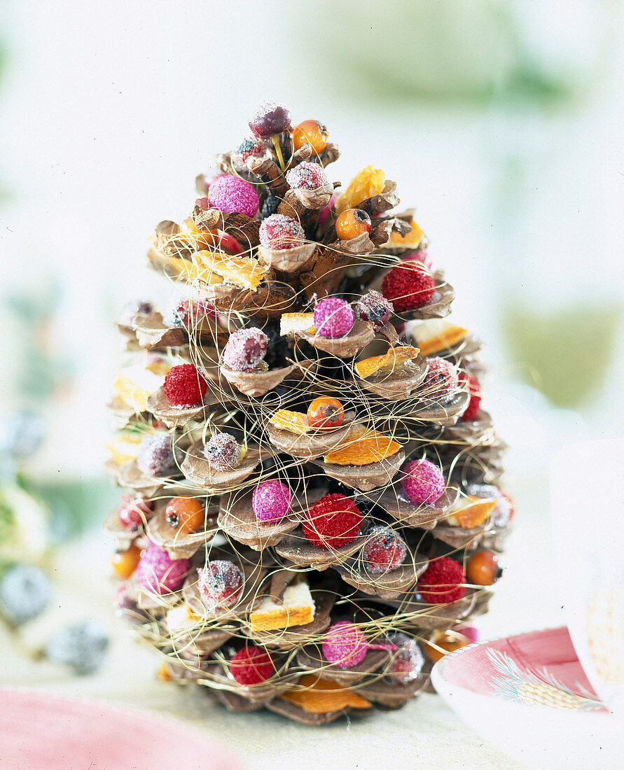 Weihnachtlich dekoriert Zapfen mit Beeren u. Bast umwickelt