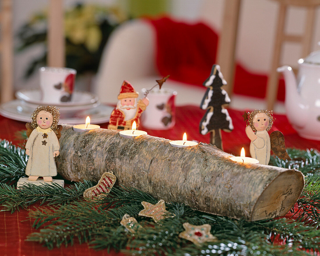 Birch trunk as Advent light holder on fir branches and wood angel