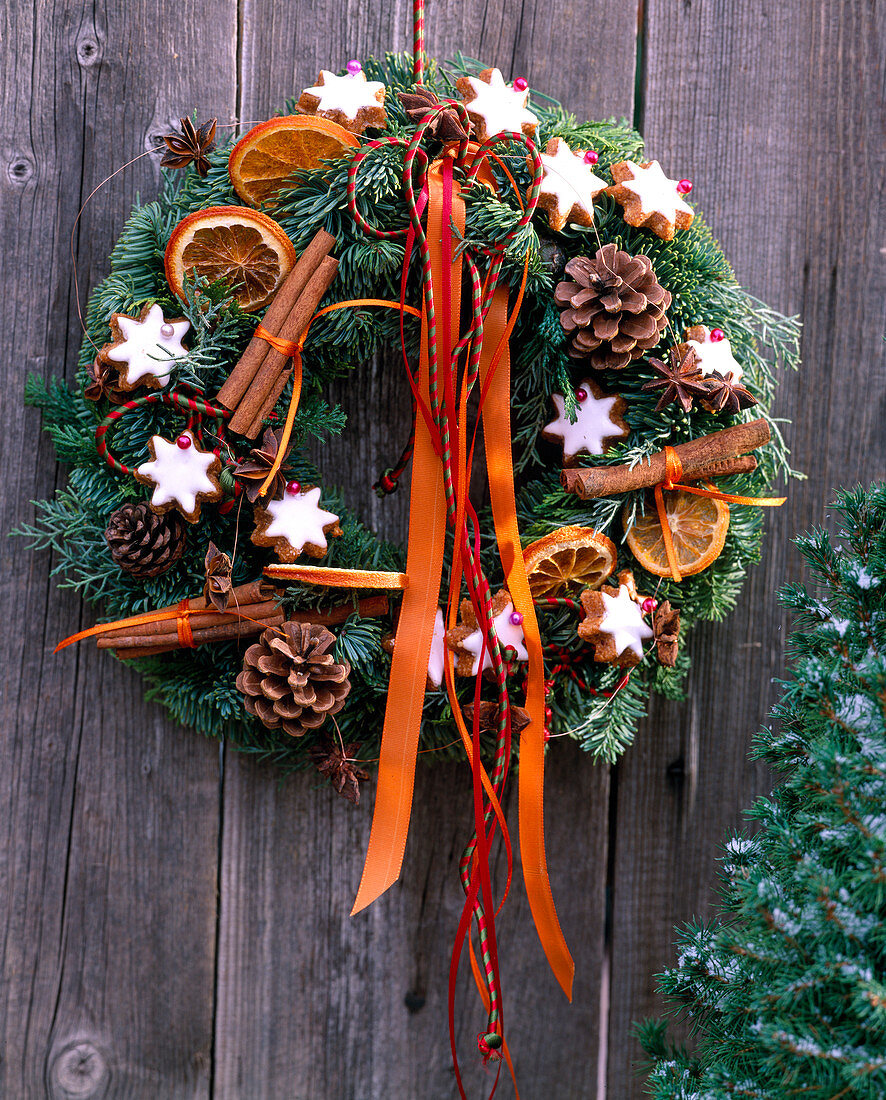 Door wreath made of twigs, cinnamon stars, cinnamon sticks, cones and ribbons