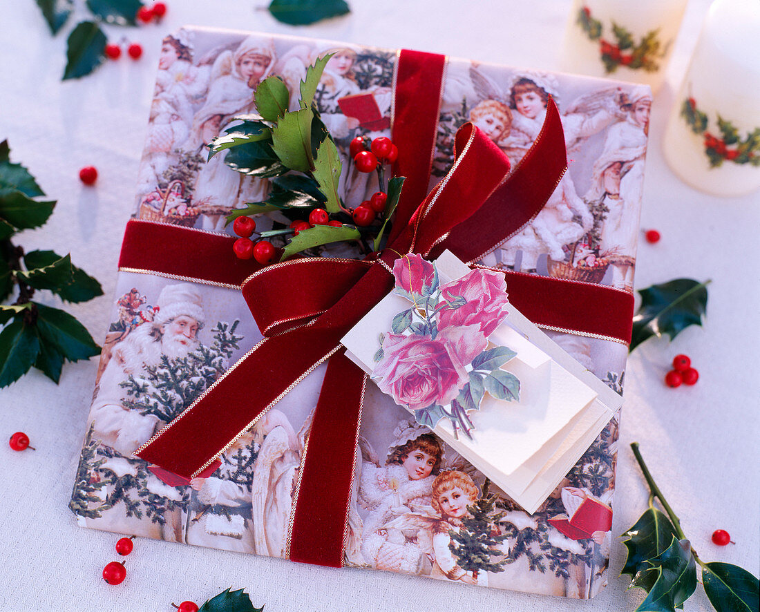 Weihnachtsgeschenk mit roter Schleife und Ilex / Stechpalme