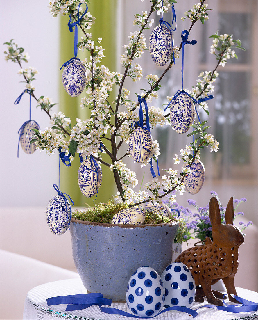 Zierapfelbäumchen als Osterdeko mit blau-weißen Ostereiern geschmückt