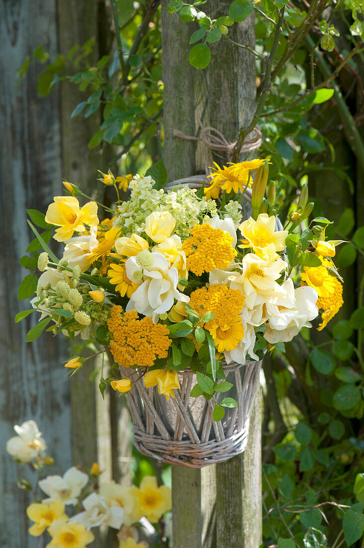 Yellow bouquet in wicker vase hung on posts