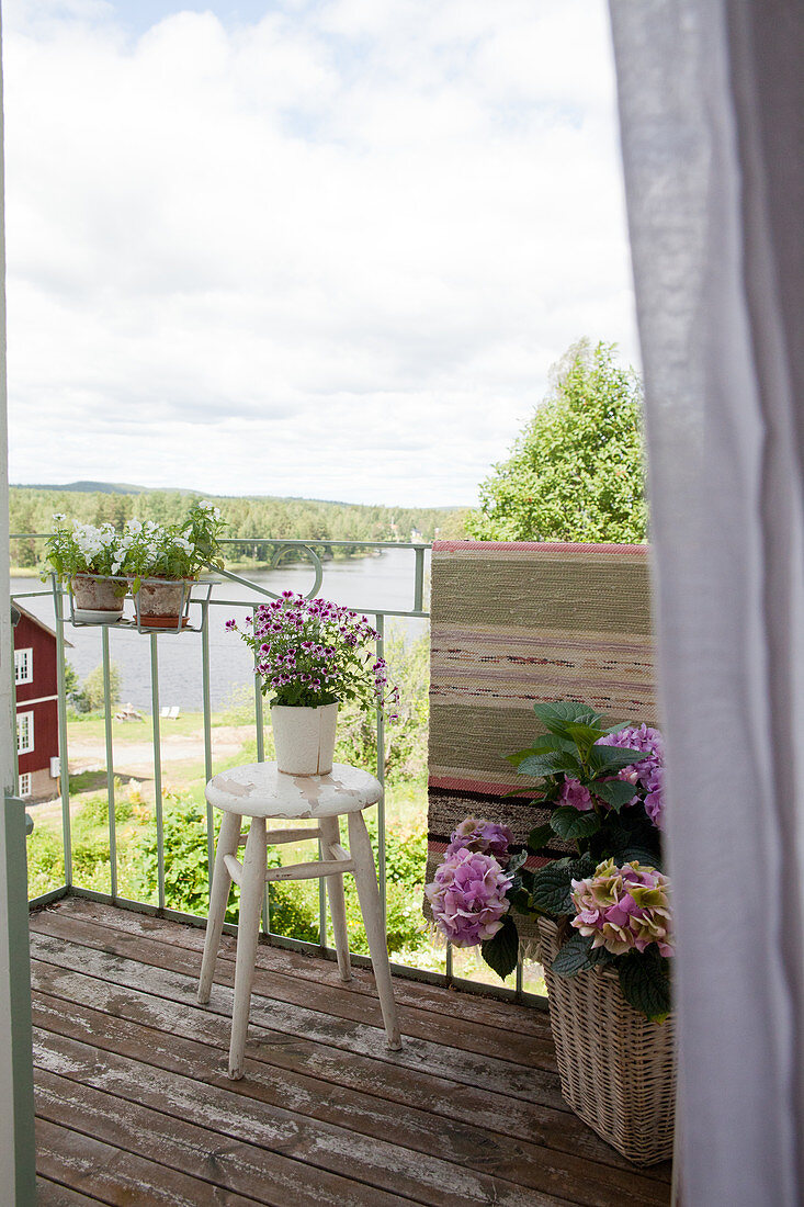 Balkon mit Hortensien mit Blick auf sommerliche Landschaft und Fjord