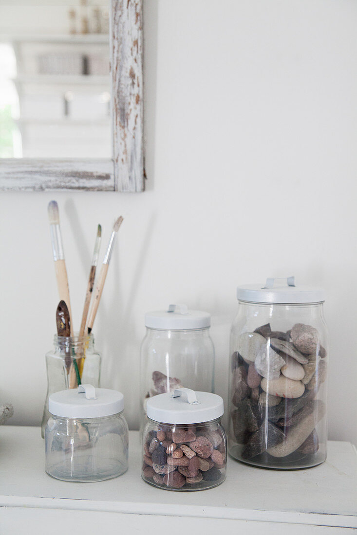 Pebbles and paintbrushes in storage jars