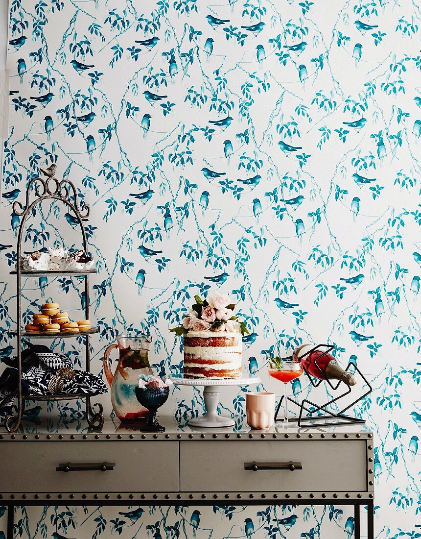 Sweet buffet on a console in front of wallpaper with bird motif