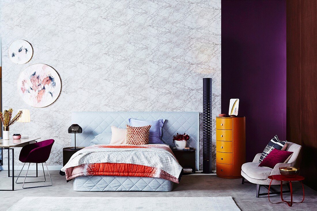 Schlafzimmer mit Wand im Marmor-Look, bunte Farbakzente