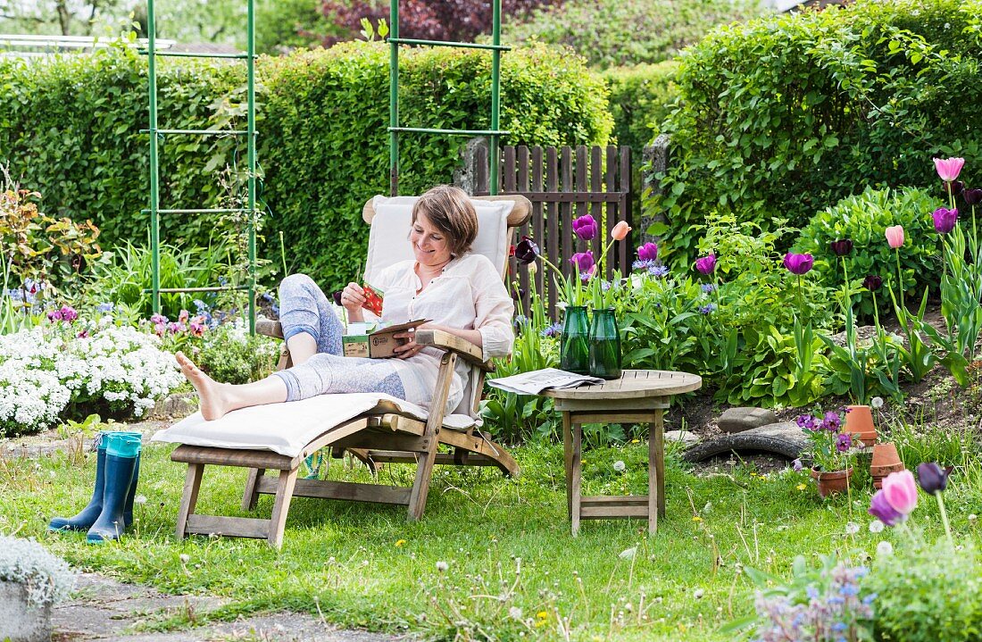 Woman on wooden lounger in idyllic allotment garden in spring