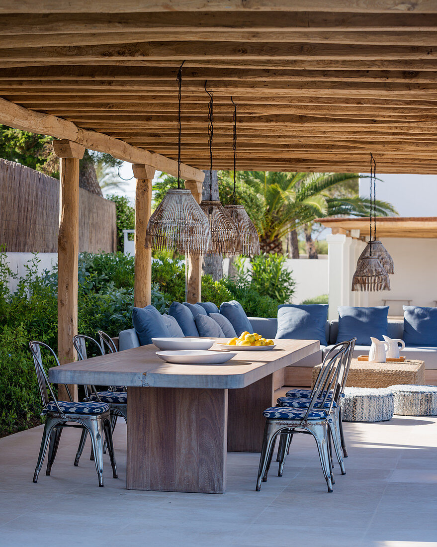 Dining table and lounge area under summery pergola