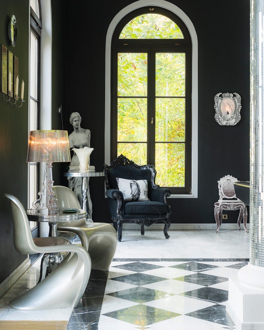 Schwarz-weißer Marmorboden und weiße Panton Chairs mit Designer-Tischleuchte vor Rundbogenfenster