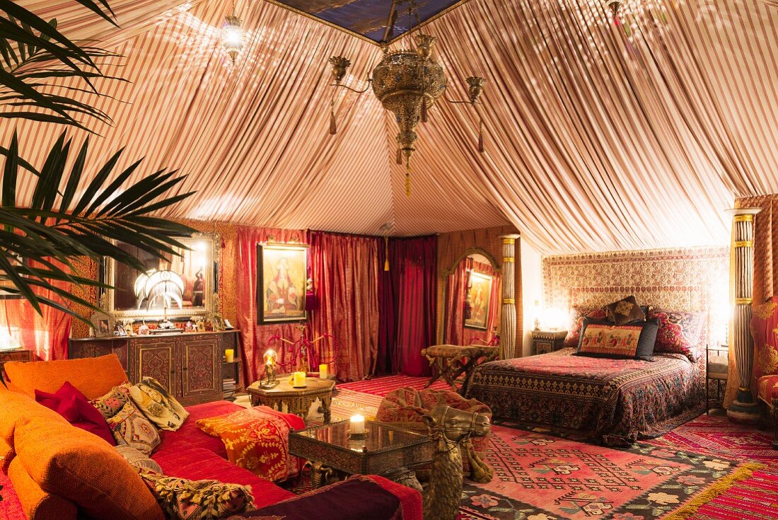 Tent style boudoir bedroom with Moroccan rugs, oriental fabrics and side table