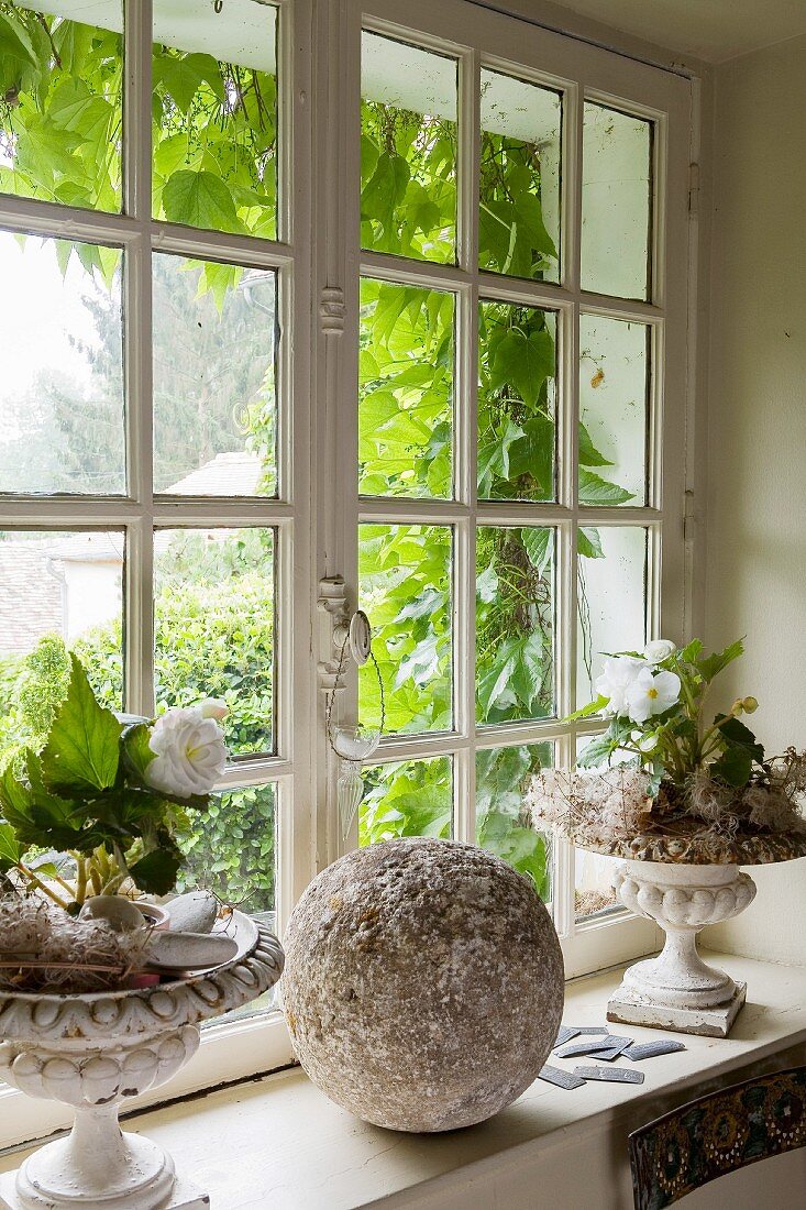 Pflanzendekoration mit Steinkugel auf Fenstersims von Sprossenfenster