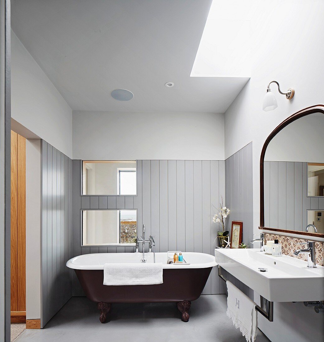 Free-standing bathtub against half-height wooden cladding in bathroom