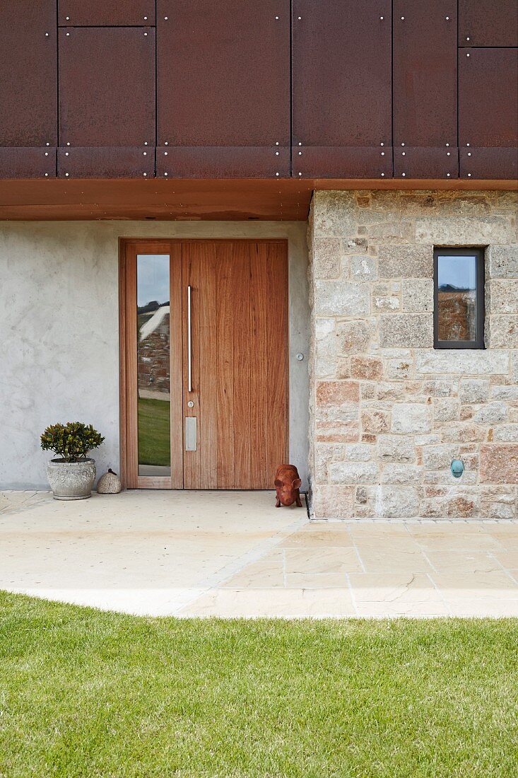 Holztür in moderner Fassade aus rostigem Metall, Naturstein und Beton