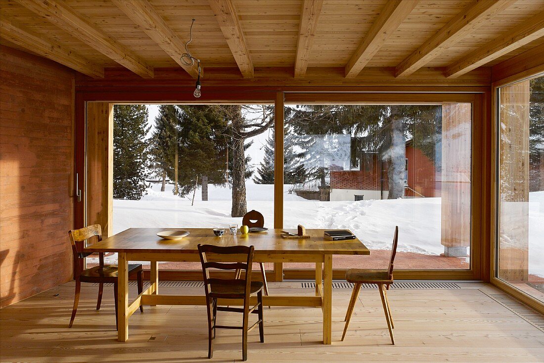 Dining room in modern wooden house with view of wintry landscape
