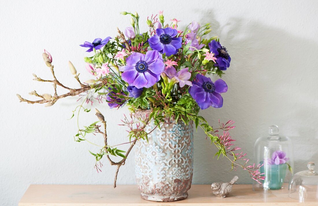 Frühlingsstrauß mit blauen Anemonen und Magnolienzweigen
