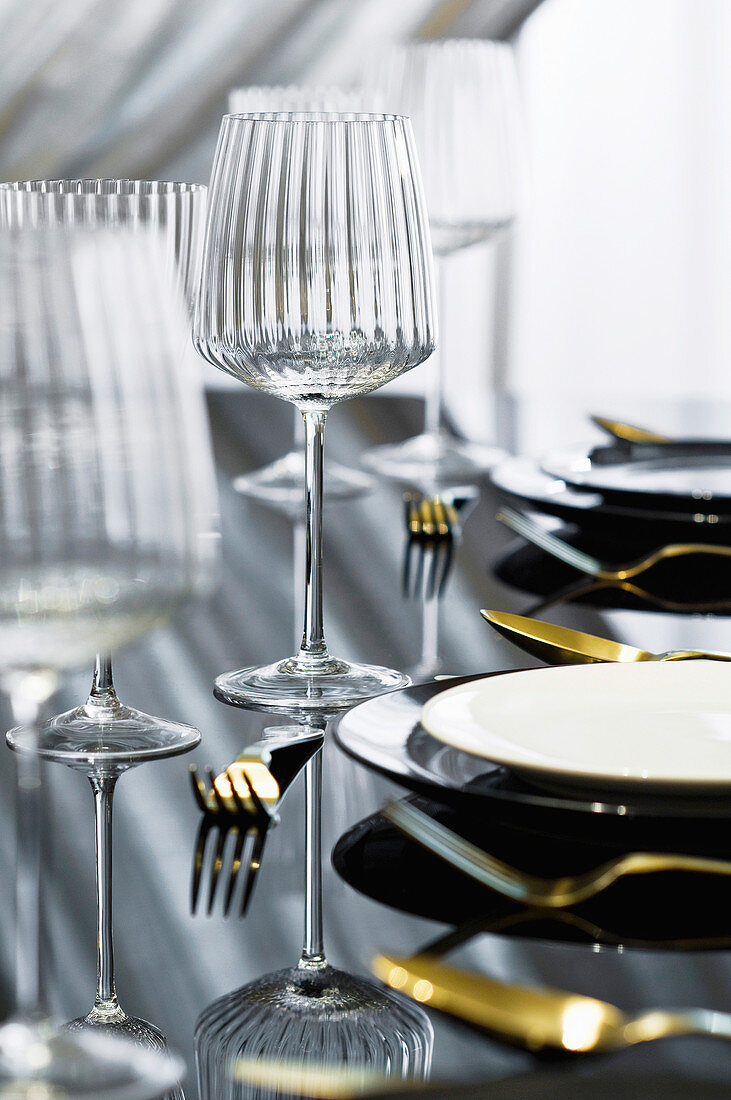 Elegantes Gedeck mit Weinglas auf schwarz glänzendem Tisch