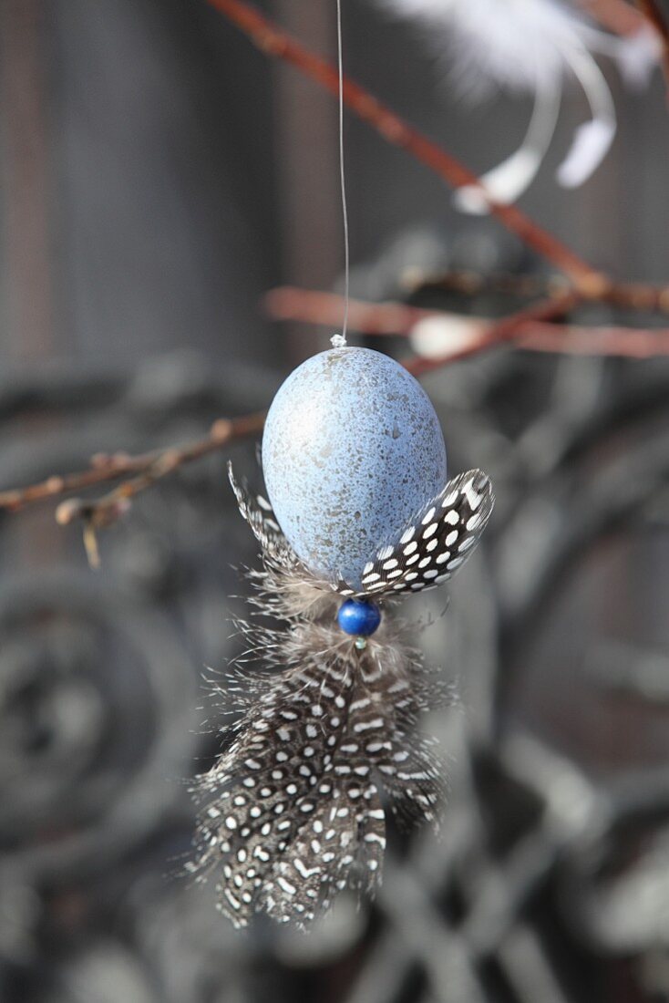 Painted speckled hen's egg decorated with feathers