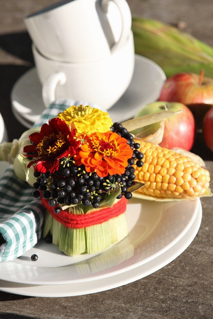 Arrangement of zinnias and dogwood berries wrapped in maize leaves