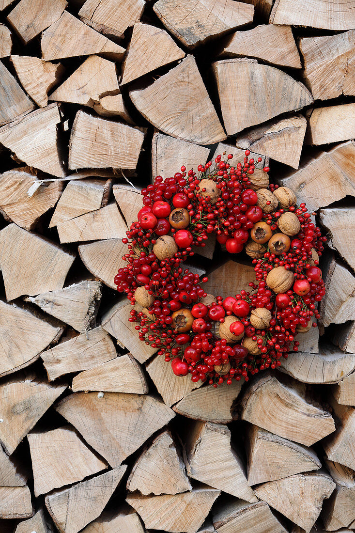 Wreath of red berries, walnuts and medlars on stacked firewood