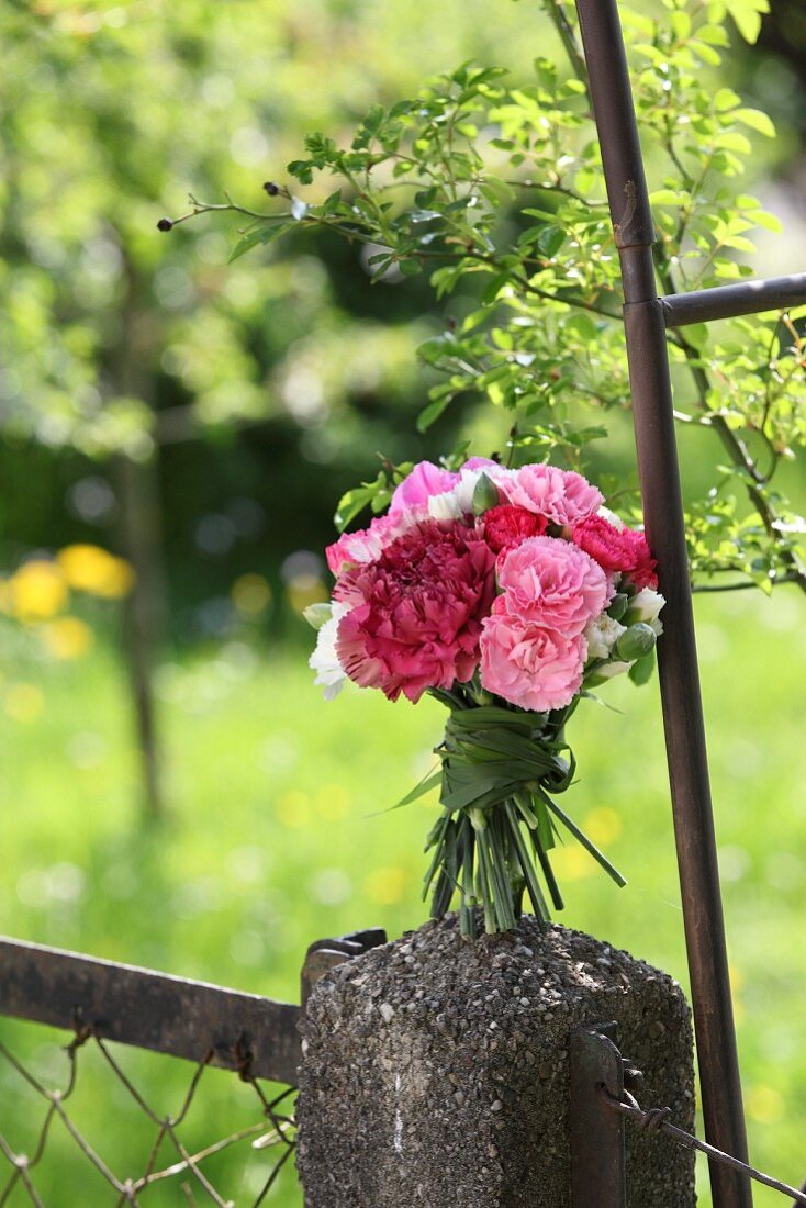 Bouquet of carnations tied with grasses on stone pillar