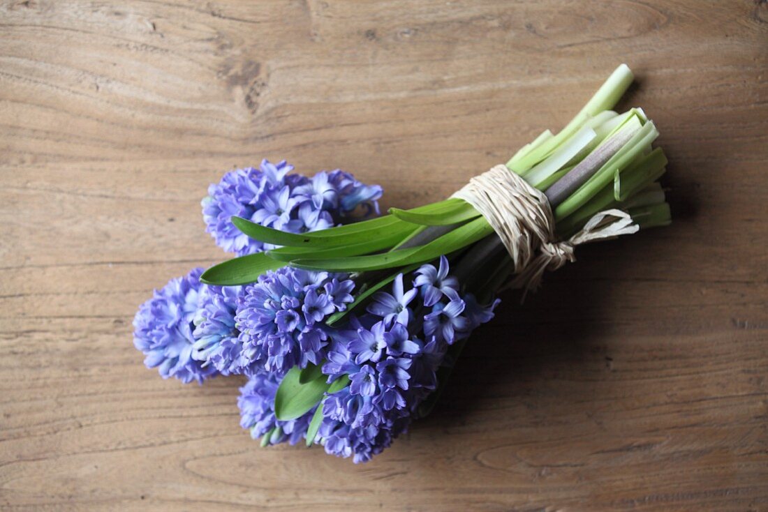 Bouquet of hyacinths tied with raffia on wooden table