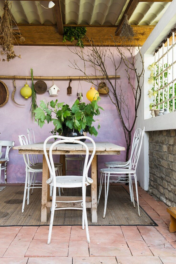 Tisch und Stühle auf mediterraner Terrasse mit lilafarbener Wand