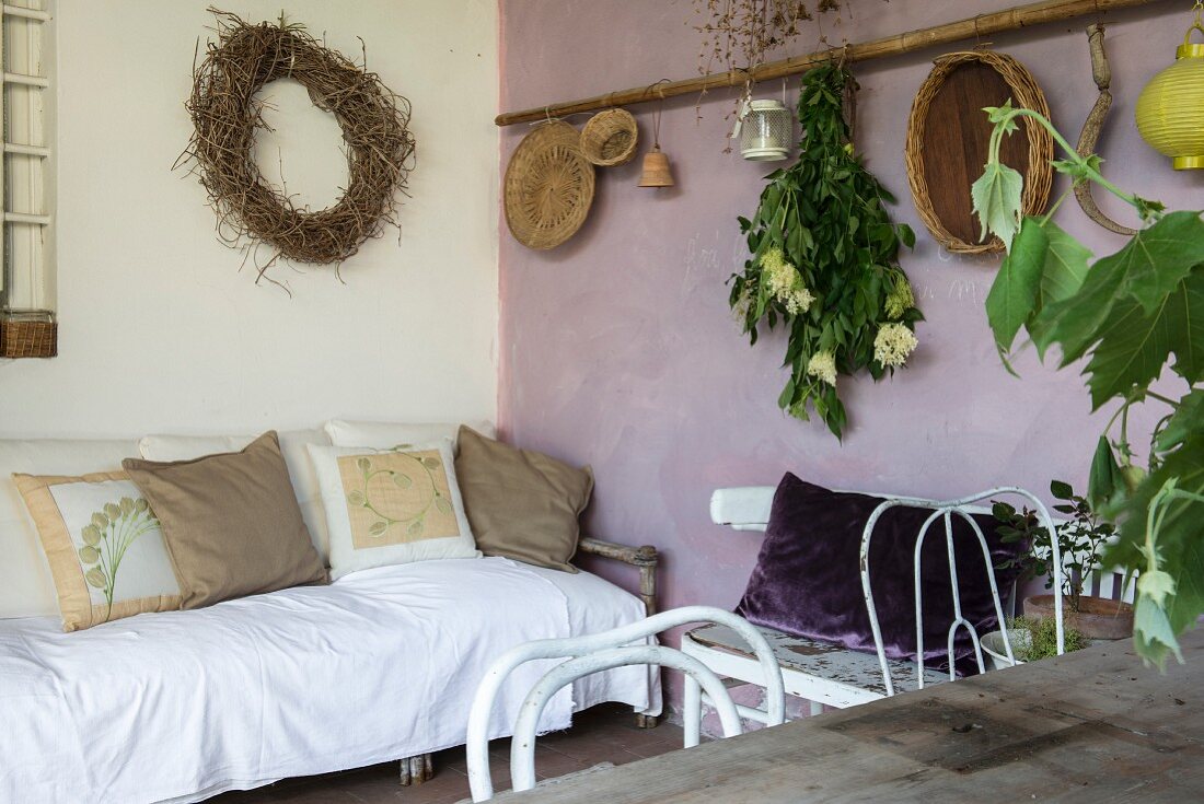 Mediterrane Loggia mit Sofa, Esstisch und lilafarbener Wand