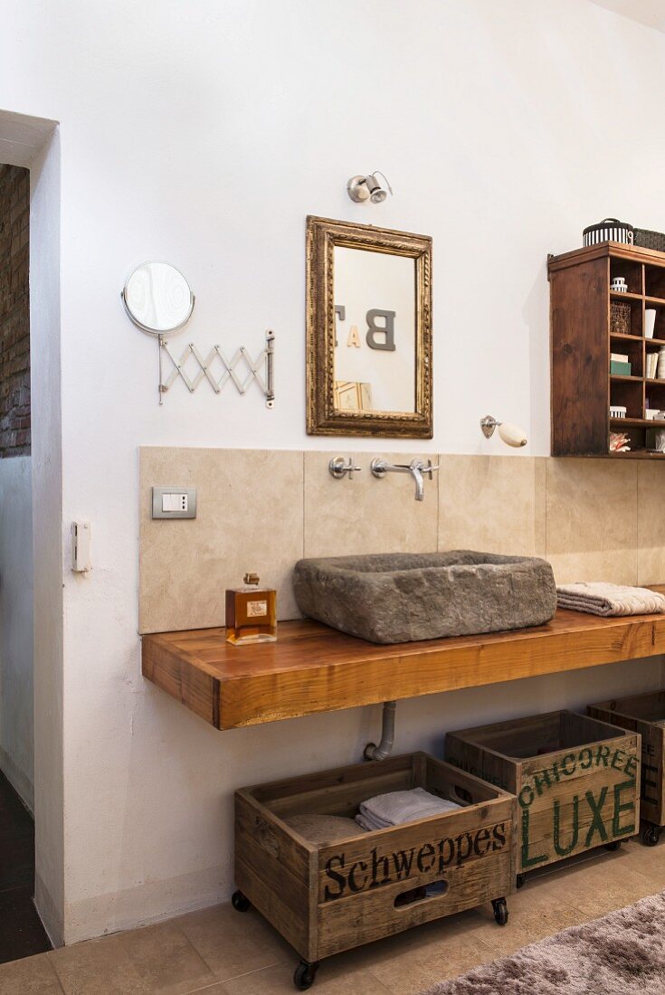 Stone sink and old wooden crates used for storage in bathroom