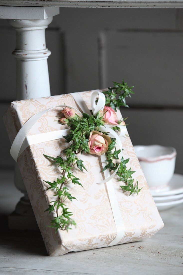 Romantically wrapped gift decorated with roses and ivy tendrils