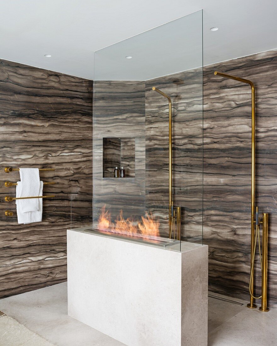 Luxus Duschbereich mit Marmorwänden und zwei Standduschen hinter Gasfeuerstelle
