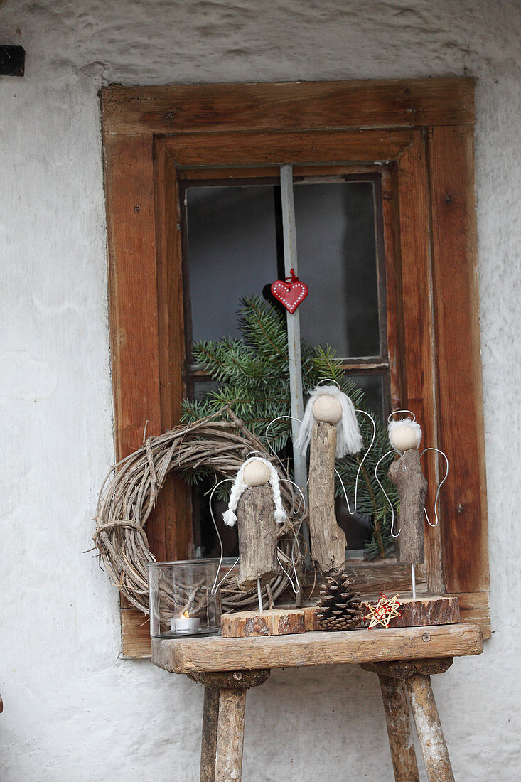 Hand-crafted driftwood angels on wooden stool in front of window