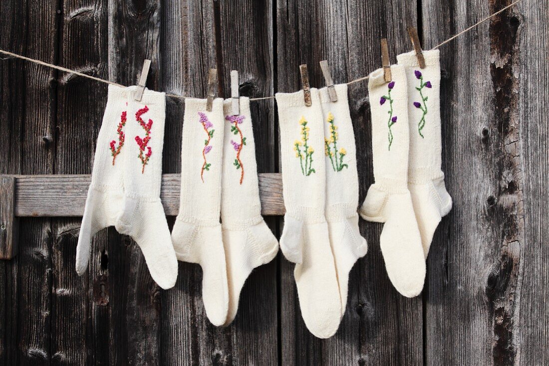 Hand-knitted woollen socks embroidered with flowers hung from washing line