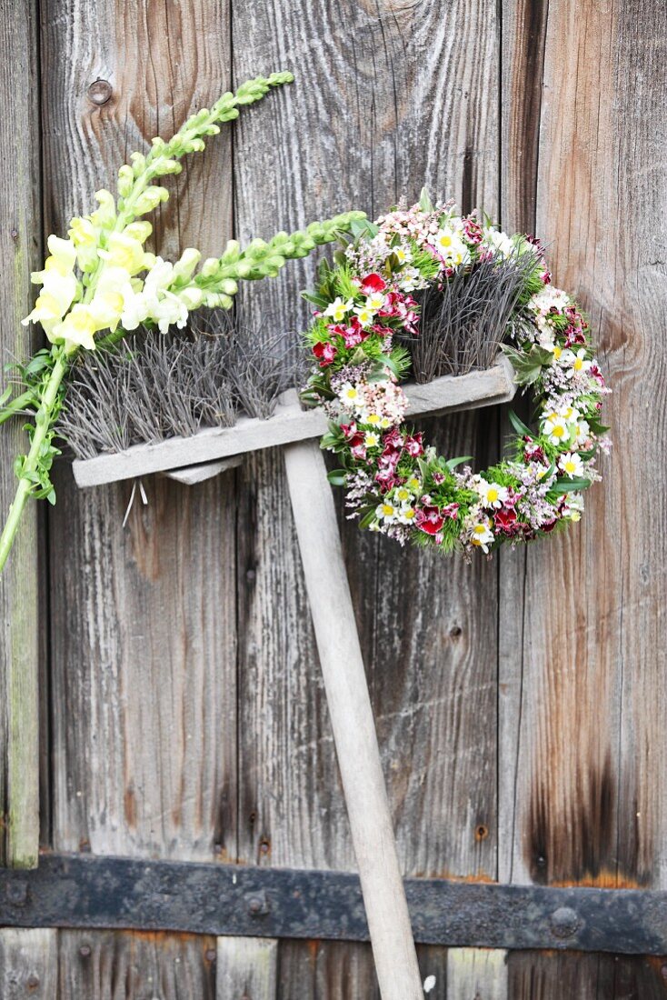 Ein Blumenkranz und zwei Löwenmäulchen an einem Besen