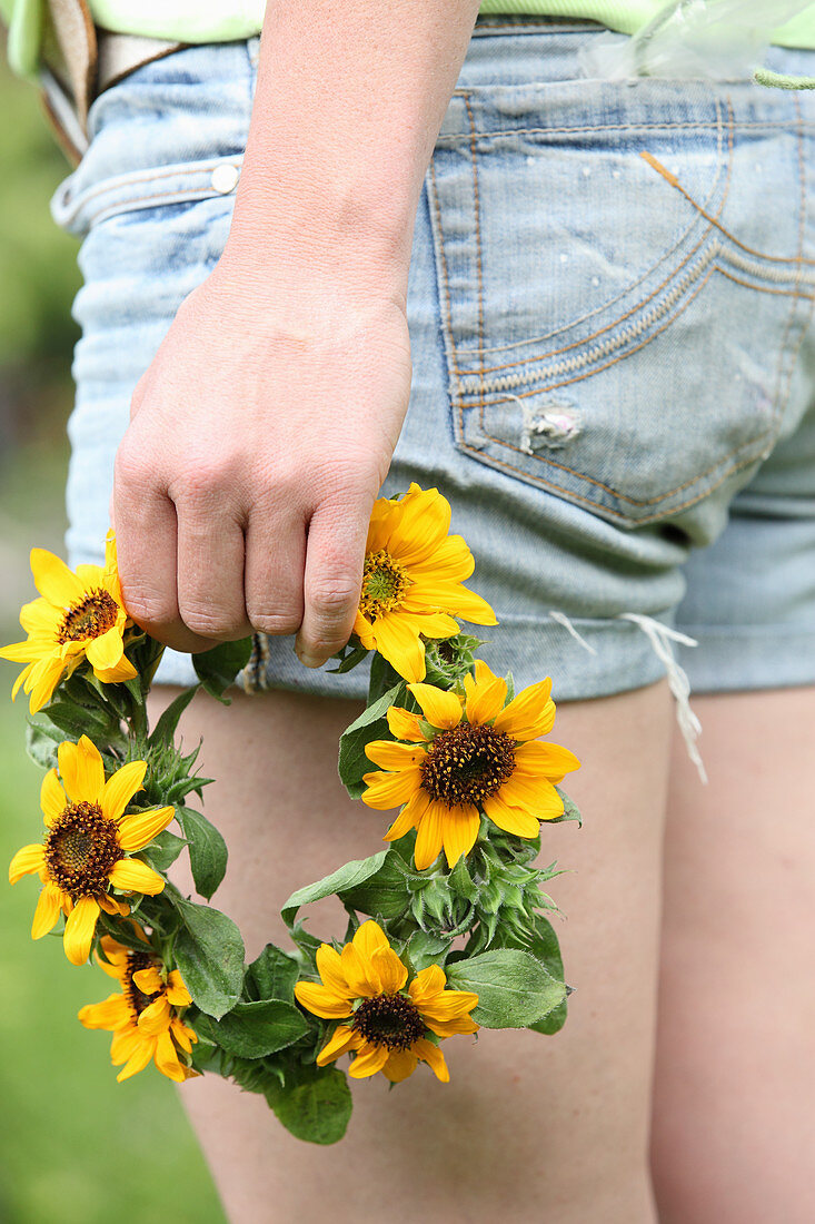 Frauenhand hält Kranz aus Sonnenblumen