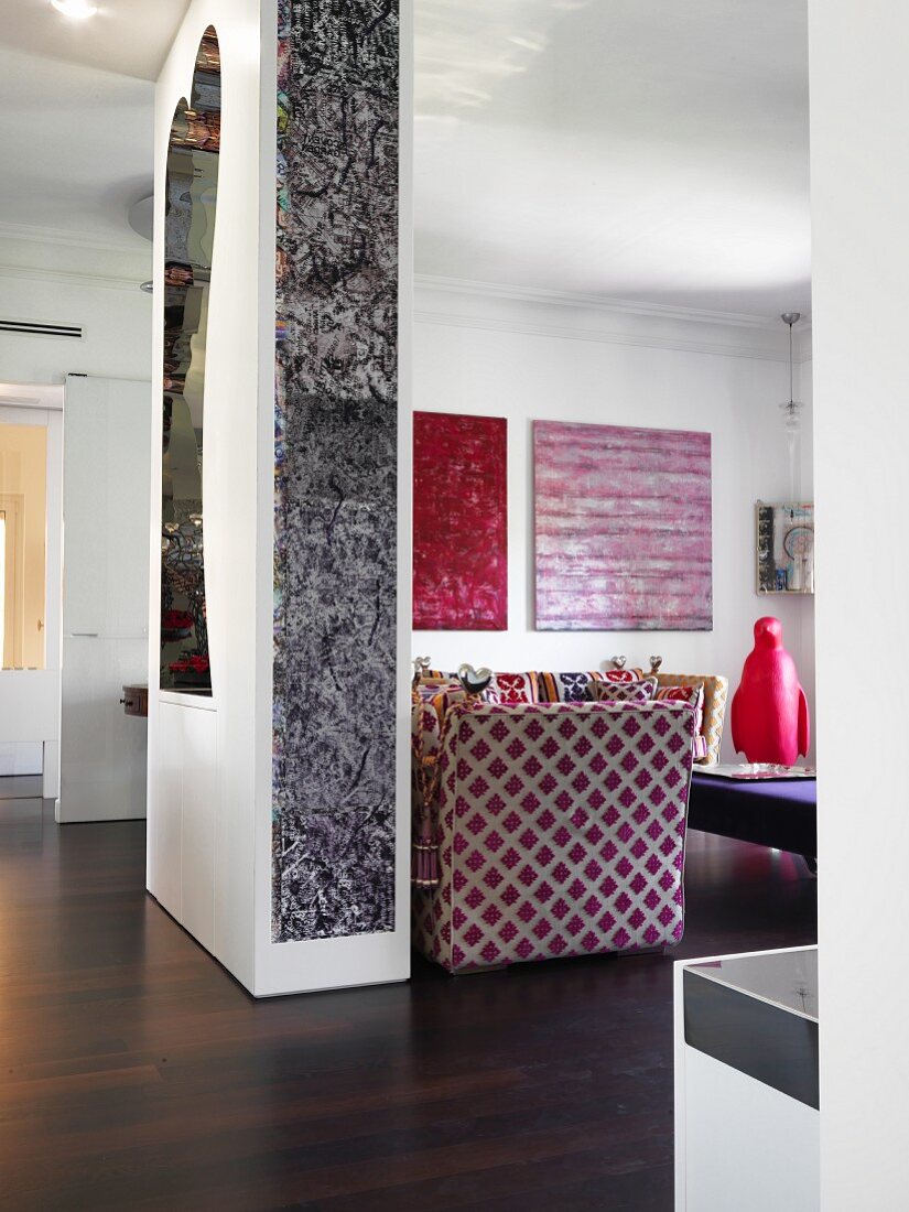 Raumteilerwand mit moderner Kunst und Spiegel, Blick in offenen Wohnbereich